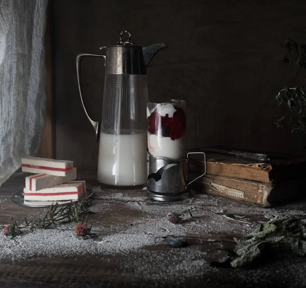 Rustic still life, vintage. dark background. milk in an old jug and  dessert in a glass. wooden table. — Stock Photo, Image
