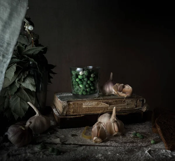 Naturaleza muerta rústica, vintage. guisantes verdes, libros viejos, ajo, harina en una mesa de madera. fondo oscuro — Foto de Stock