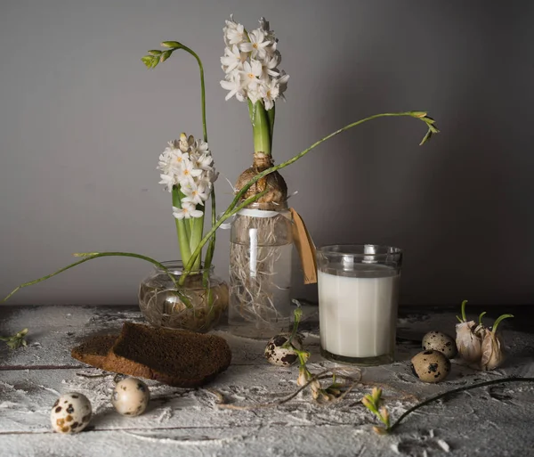 Still life with milk, bread, eggs and hyacinths in glass vases. — Stock Photo, Image