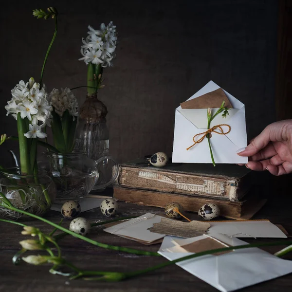 Mão feminina segurando uma carta com o envelope no fundo escuro . — Fotografia de Stock