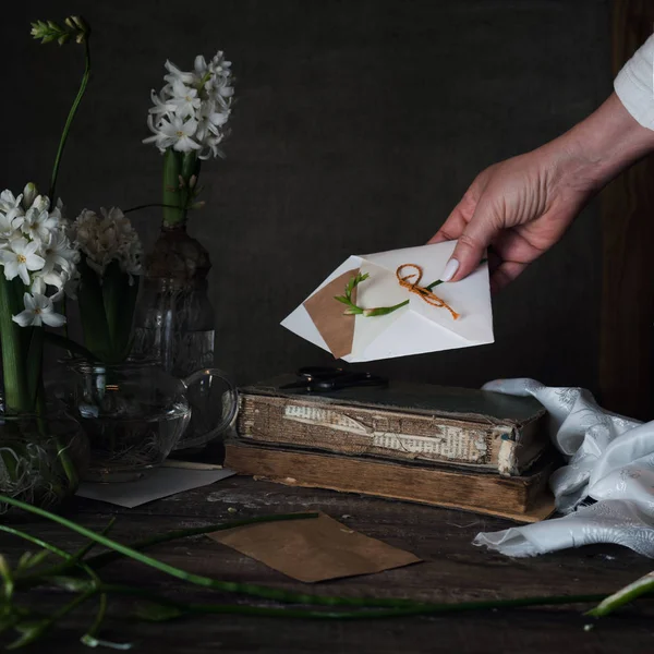 Vrouwelijke hand stak een brief met de envelop op donkere achtergrond — Stockfoto