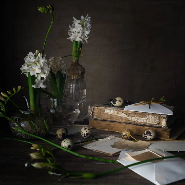 Naturaleza muerta con libros antiguos, huevos de codorniz, jacintos blancos sobre un fondo oscuro . —  Fotos de Stock