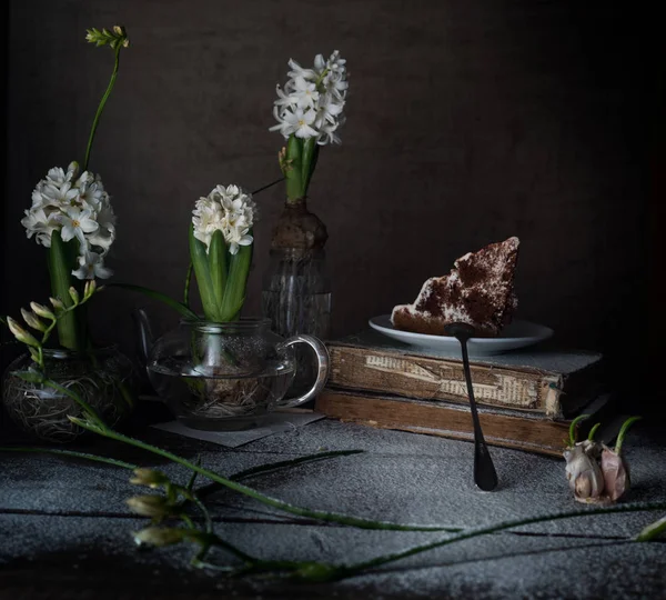 Naturaleza muerta con libros antiguos, pastel, jacintos blancos sobre un fondo oscuro . — Foto de Stock