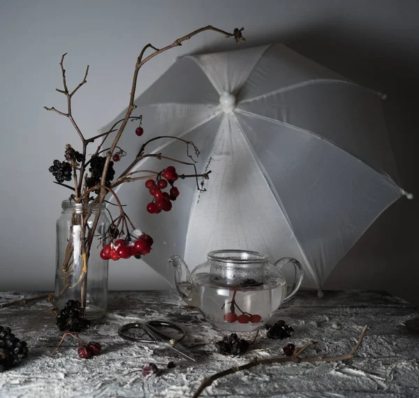 Viburnum takken met bessen en sneeuw in een doorzichtige vaas, paraplu op houten tafel — Stockfoto