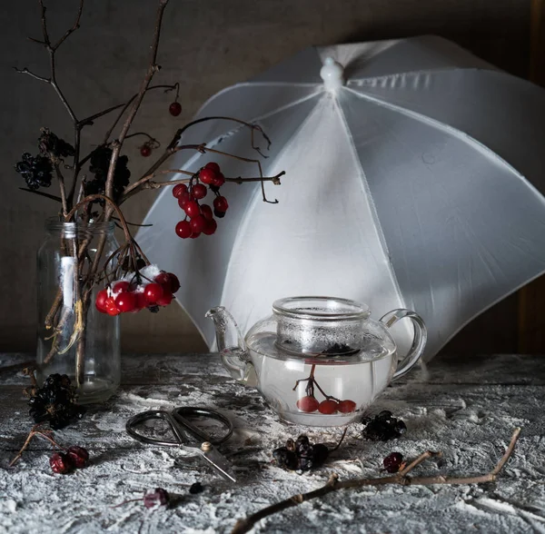 Βιβούρνο κλαδιά με μούρα και το χιόνι σε ένα διαφανές βάζο, ομπρέλα στο ξύλινο τραπέζι — Φωτογραφία Αρχείου