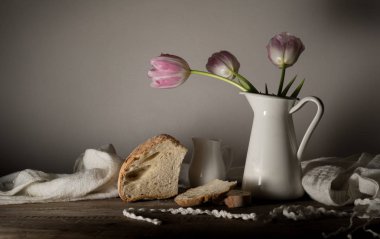 rustik natürmort. Lale, taze ekmek, süt ahşap bir masa üzerinde buket. siyah arka plan