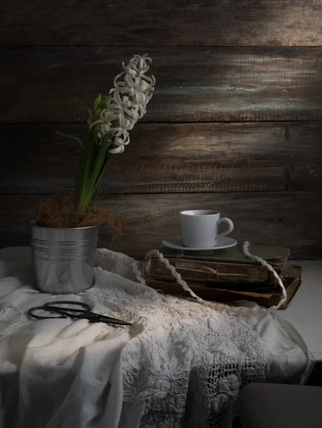 Stilleven met hyacint, kopje koffie, oude boeken, schaar op een achtergrond van ruwe houten muren. Vintage. — Stockfoto