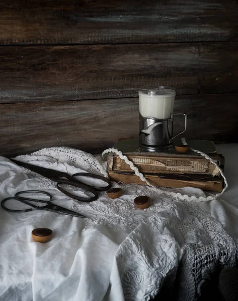 静物与旧书、 剪刀和一杯牛奶，背景为粗糙的木墙。年份 — 图库照片