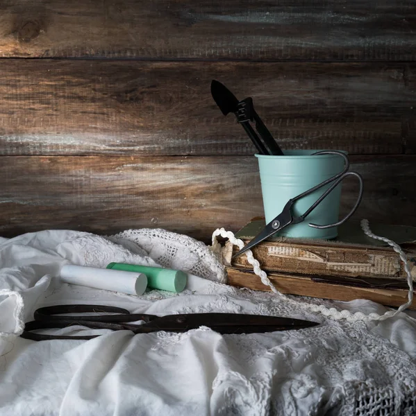 Nature morte con forbici, pastelli e merletti su uno sfondo di pareti di legno grezzo. vintage — Foto Stock