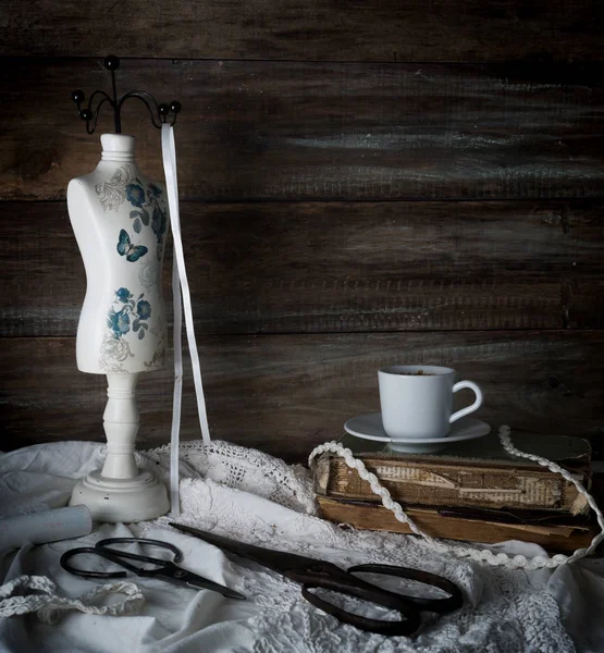 静物与一杯咖啡、 剪刀、 模特缝纫和背景的粗糙的木墙壁上的花边。年份 — 图库照片