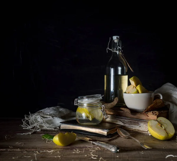 Still life with apples, apple juice, old books and a silver knife on a wooden table on a dark background. vintage — Stock Photo, Image