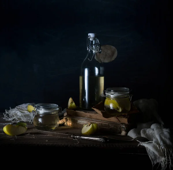 Stilleven met appels, appelsap, oude boeken en een zilveren mes op een houten tafel op een donkere achtergrond. Vintage — Stockfoto