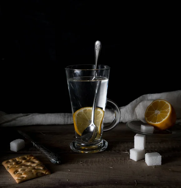 Ρουστίκ νεκρή. Τσάι με λεμόνι σε ένα μεγάλο κύκλο πάνω στο ξύλινο τραπέζι. μαύρο φόντο — Φωτογραφία Αρχείου