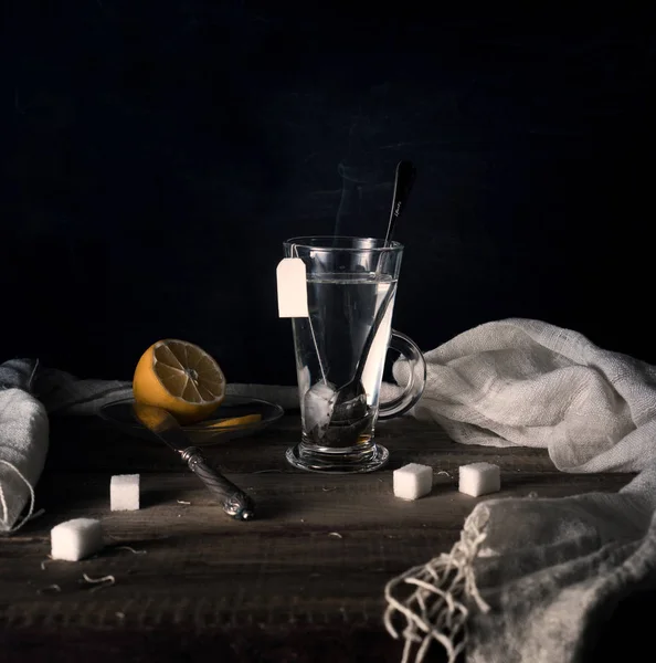 Rustieke stilleven. Thee met citroen in een grote cirkel op de houten tafel. zwarte achtergrond — Stockfoto