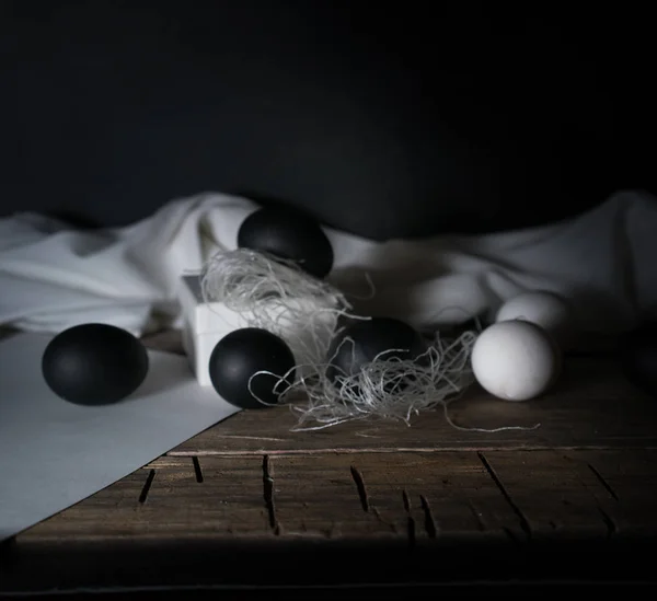 BlackEaster. Noche de Pascua. Huevos blancos y negros, plumas sobre una mesa de madera. Vintage. Fondo oscuro —  Fotos de Stock