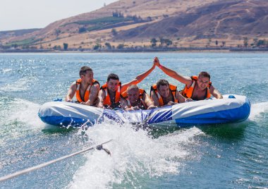 Grup genç adam şişme bir cazibe üzerinde yüzen