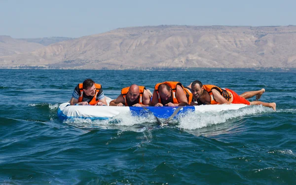 Groupe de jeunes hommes flottant sur une attraction gonflable — Photo
