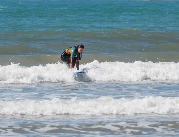 Menina na cor terno impermeável exercitando-se no surf a bordo — Fotografia de Stock