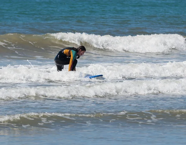 Menina na cor terno impermeável exercitando-se no surf a bordo — Fotografia de Stock