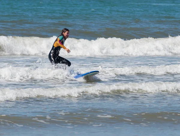 Menina na cor terno impermeável exercitando-se no surf a bordo — Fotografia de Stock