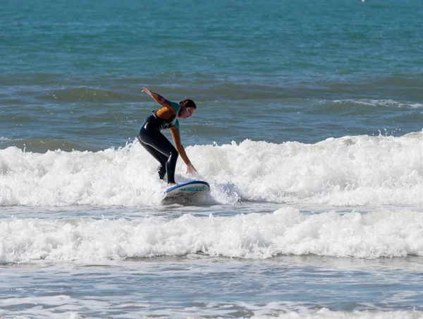 Menina na cor terno impermeável exercitando-se no surf a bordo — Fotografia de Stock