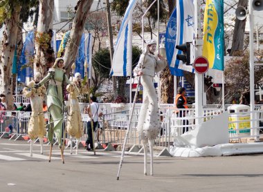 Katılımcılar carnival stilts, cadde boyunca yürüyor
