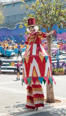 Palyaço stilts üzerinde ilgi çekici yerlere park ziyaretçilerine selamlıyor