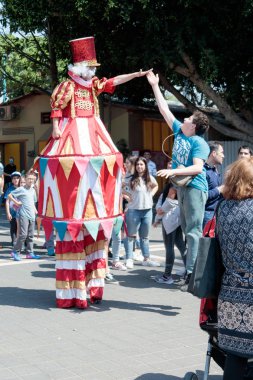 Palyaço stilts üzerinde ilgi çekici yerlere park ziyaretçilerine selamlıyor