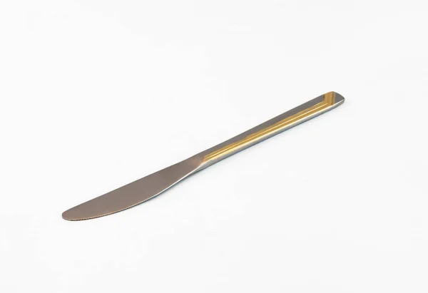 Couteau de table en argent avec des rayures dorées sur la poignée sur un dos blanc — Photo