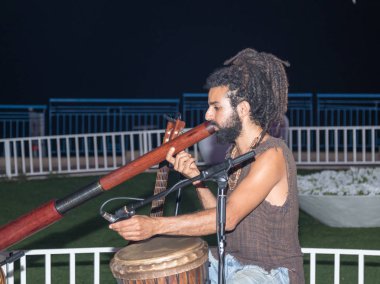 Genç bir adam büyük bir boru akşam şehir Nahariya, İsrail waterfront üzerinde çalış