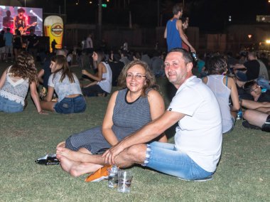 Memnun ziyaretçilerin çimenlerin üzerinde otur ve Hayfa İsrail geleneksel yıllık Bira Festivali dinlen