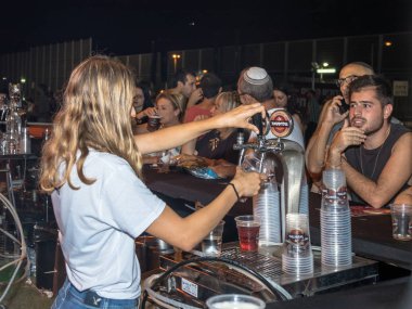 Satıcı ziyaretçi için soğuk taze bira Hayfa İsrail geleneksel yıllık Bira Festivali plastik bardakta içki alıyor