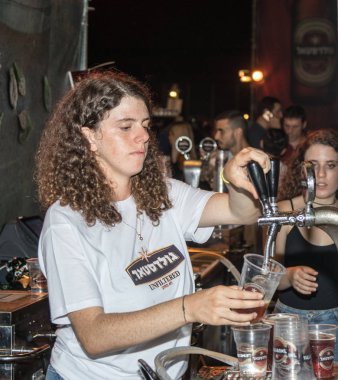 Satıcı ziyaretçi için soğuk taze bira Hayfa İsrail geleneksel yıllık Bira Festivali plastik bardakta içki alıyor