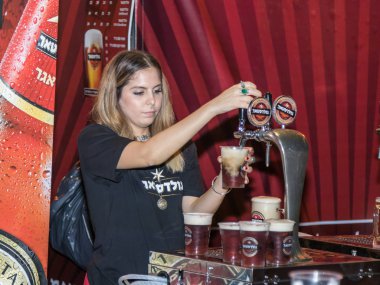 Satıcı ziyaretçi için soğuk taze bira Hayfa İsrail geleneksel yıllık Bira Festivali plastik bardakta içki alıyor