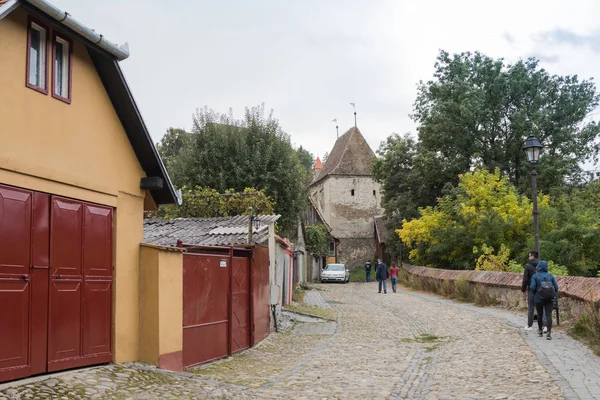 Los turistas caminan por las tranquilas calles de la ciudad vieja y visitan los lugares de interés de la ciudad de Sighisoara en Rumania — Foto de Stock