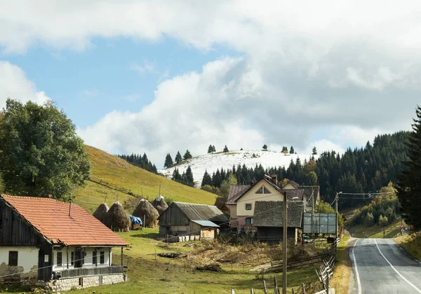 A estrada que passa pela aldeia ao pé das montanhas dos Cárpatos perto da cidade de Bran, na Roménia — Fotografia de Stock