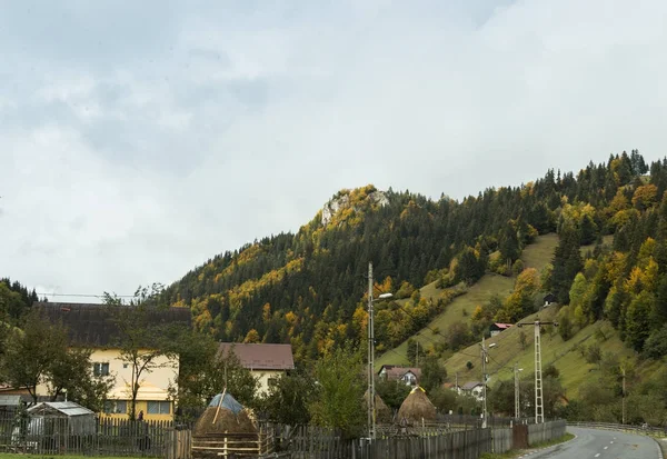 A estrada que passa pela aldeia ao pé das montanhas dos Cárpatos perto da cidade de Bran, na Roménia — Fotografia de Stock