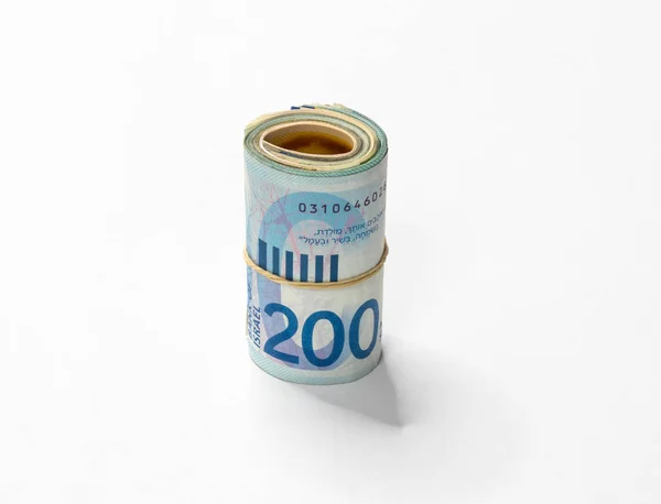 Ett gäng nya israeliska shekel (Nis) pengar anteckningar rullas upp och hålls ihop med en enkel gummisnodd isolerad på en vit bakgrund. — Stockfoto