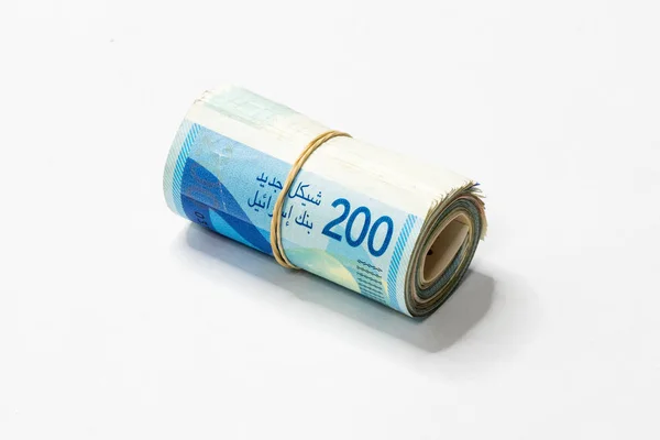 Een bos van Israëlische nieuwe sikkels (NOS) geld notities opgerold en samengehouden met een eenvoudig elastiekje geïsoleerd op een witte achtergrond. — Stockfoto