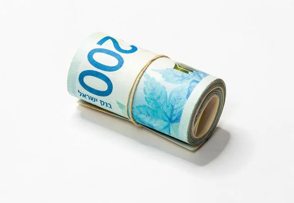 Ein Bündel neuer israelischer Schekel (nis) Geldscheine zusammengerollt und mit einem einfachen Gummiband auf weißem Hintergrund zusammengehalten. — Stockfoto