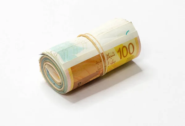 Ett gäng nya israeliska shekel (Nis) pengar anteckningar rullas upp och hålls ihop med en enkel gummisnodd isolerad på en vit bakgrund. — Stockfoto
