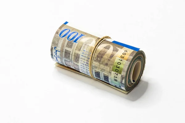 A bunch of Israeli New Shekels (NIS) money notes rolled up and held together with a simple rubber band isolated on a white background. Stock Picture