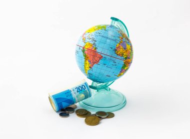 Bir küre şeklinde yapılmış bir para kutusu üst para yuvalı Dünya gezegeninin toplu ayağa kalkar ve birkaç sikke, beyaz bir arka plan üzerinde izole ile farklı değerinin İsrail banknotlar yığını bir arada tutan.