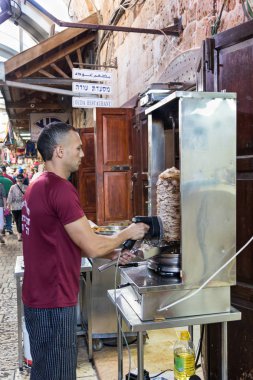 Satıcı ızgara elektrik shawarma müşteriler için İsrail eski kasaba Acre piyasada keser