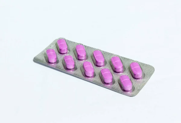 Balení 10 růžové podlouhlé pilulek izolovaných na bílém pozadí — Stock fotografie