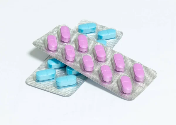 One package with pink and one package with blue oblong pills isolated on a white background — Stock Photo, Image