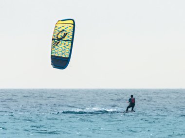 Karanlık su geçirmez elbiseli genç adam kiteboarding Akdeniz denize yakın Nahariyya, İsrail üzerinde rüzgarlı havalarda devreye girer