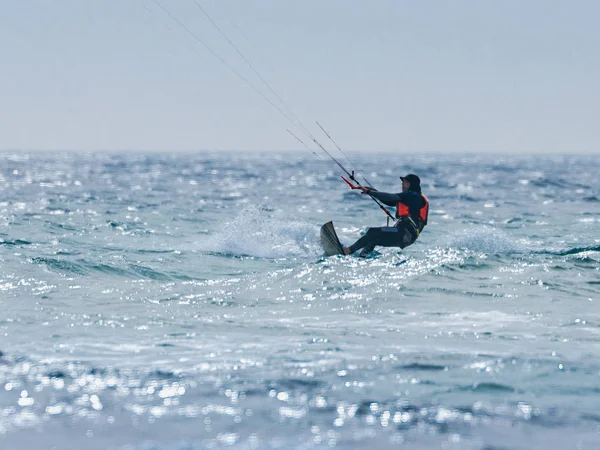 Jovem em um terno impermeável escuro está envolvido em kiteboarding em tempo ventoso no Mar Mediterrâneo perto de Nahariyya, Israel — Fotografia de Stock
