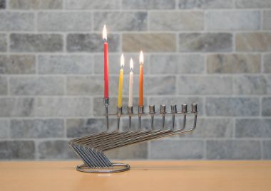 Hanuka kutlaması için metal bir şamdan ile yanan mumlar bir tuğla duvar zemin karşı masada duruyor