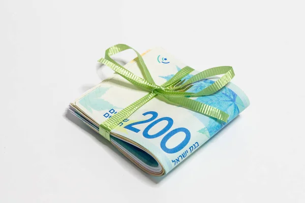 A stack of folded new Israeli banknotes of different value in shekels (NIS)  tied with green ribbon  isolated on a white background — Stock Photo, Image